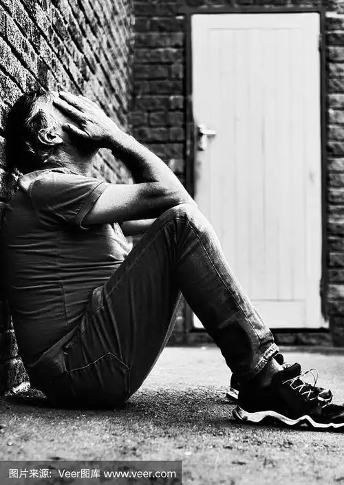 绝望的中年男子独自坐在那里,用手捂着脸