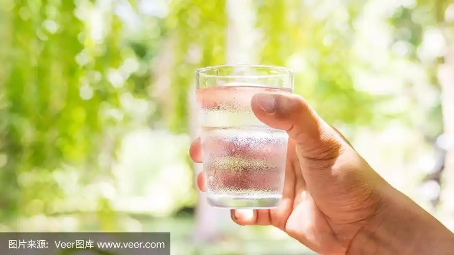一个人拿着一杯水在自然背景下.