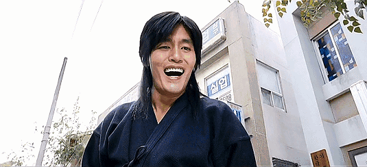 崔成国饰演的"剑道金馆长"和小孩在街头玩游戏机,作弊获胜后哈哈大笑