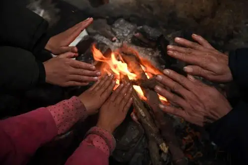 1月10日,在芝打教学点,陈万荣和两名学生围在火塘边烤火.
