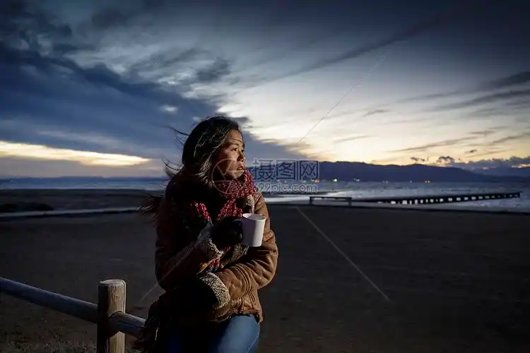 分西班牙加泰罗尼亚塔拉戈纳一名裹着围巾的年轻女子从海滩上回头望去