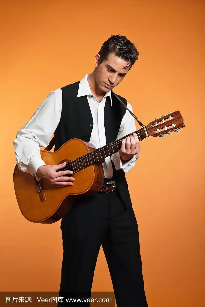 穿着黑色西装的复古乡村男吉他手.影棚拍摄.