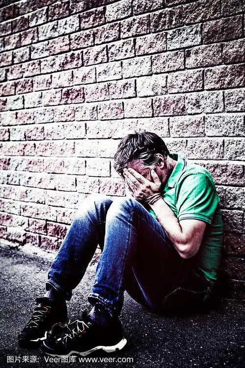 双手捂着脸,绝望的男人蹲着哭泣