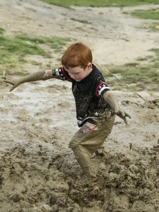 一个女孩侧躺在泥浆里,满身都是泥巴,毫不嫌弃(图片来自东方ic)