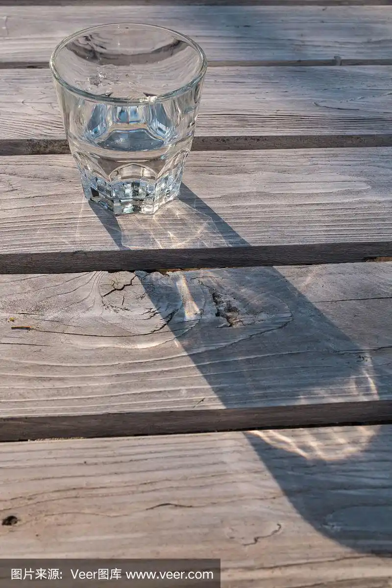 水杯的影子投射在木桌上