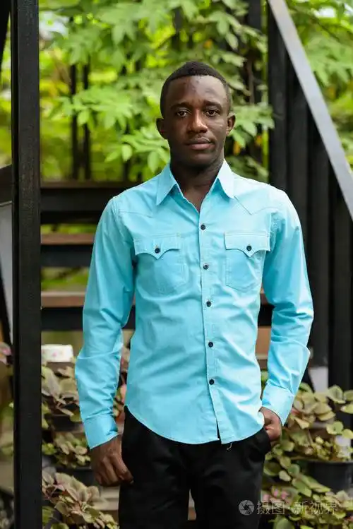 年轻的黑人非洲人站立反对现代楼梯与n