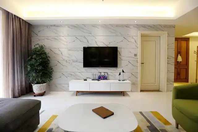 客厅电视墙上铺着大理石质感的瓷砖,壁挂式电视,搭配一张白色