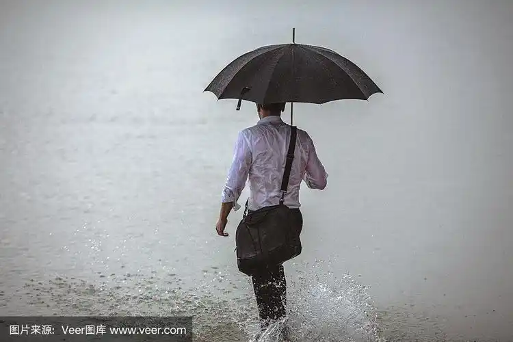 帅男撑着伞在雨中走过