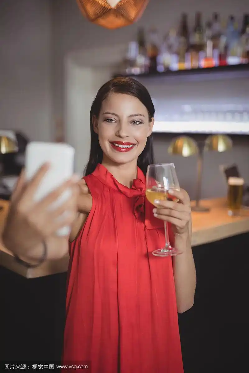 一名女子在餐厅喝酒时用手机自拍