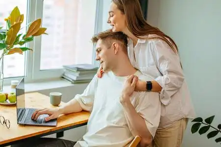 美丽的妻子支持丈夫在家工作,自由职业概念照片