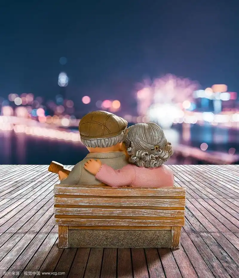快乐老两口依偎在椅子上的背影背后是美丽城市夜景