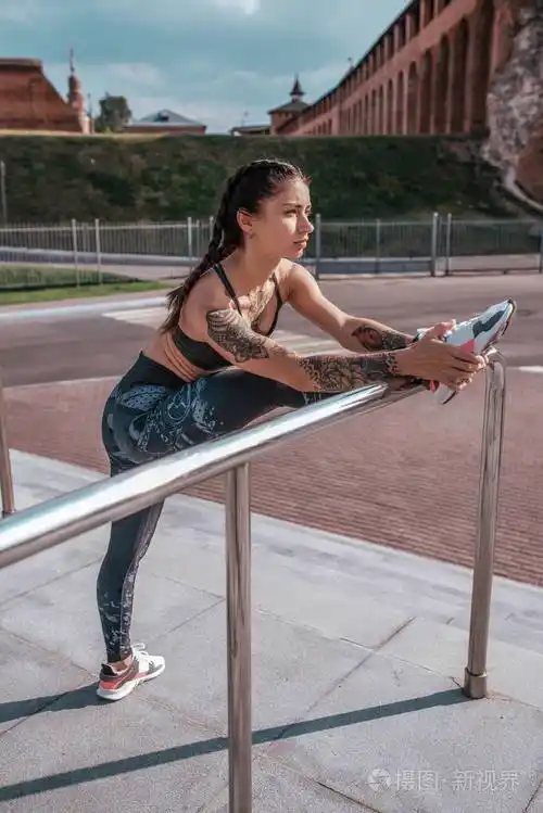 穿着紧身裤运动鞋.有纹身的女人.慢跑前跑步.伸展小腿的肌肉在分裂