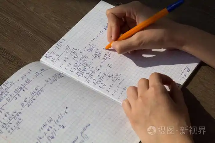 女性手在笔记本中写数学公式.数学中的学校作业