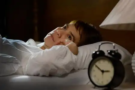 睡觉妻子安慰失眠的丈夫失眠症床头柜上的闹钟失眠的妇女在床上醒来