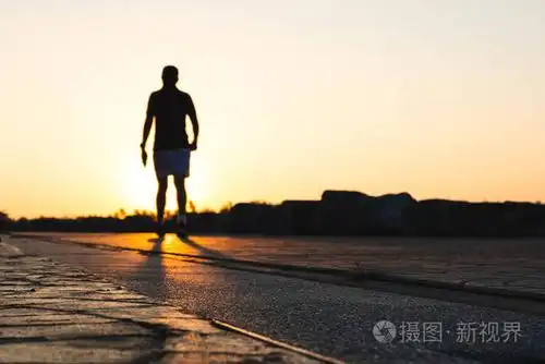 傍晚日落时,年轻人跑步的剪影正在公园里跑步. 人们散步和锻炼.