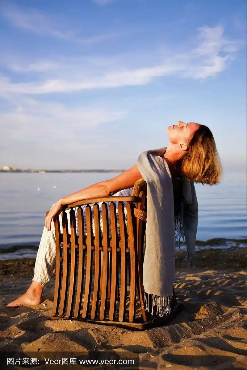 年轻漂亮的女人在海滩上晒太阳