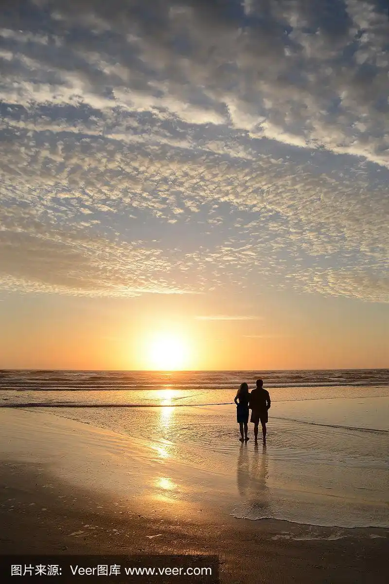 日出时分,一对情侣在海滩上放松.