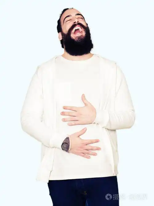 留着长发和胡须,穿着运动型运动衫,微笑着,大声笑,因为有趣的疯狂笑话