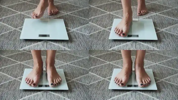 在家里,女人站在秤上称体重