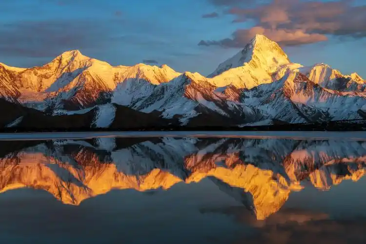 夕阳灿世辉日落时分夕阳的余晖点燃了贡嘎雪山金色的雪峰倒影在纯净的