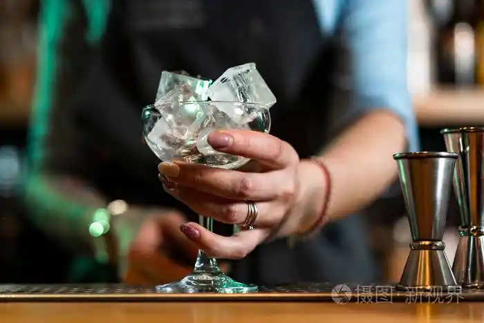 酒吧里一个女人手里拿着酒杯里的冰块