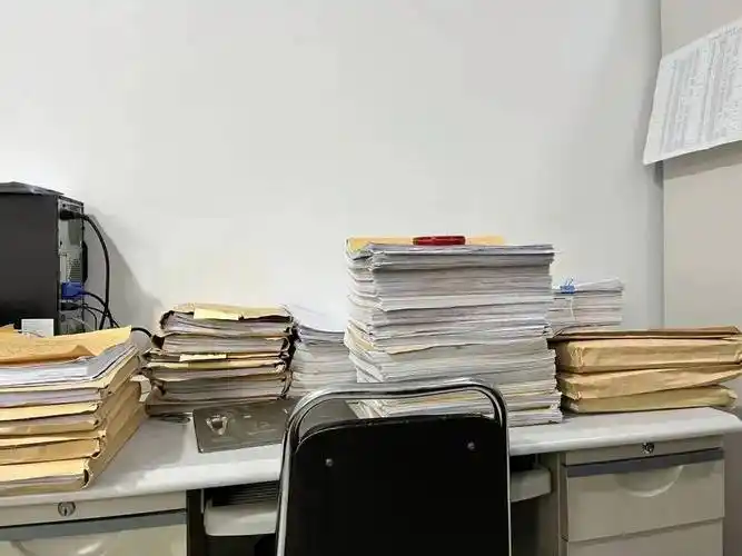 在不到10平米的房间里,每张桌子上都堆满了一摞一摞的卷宗,让5个人的